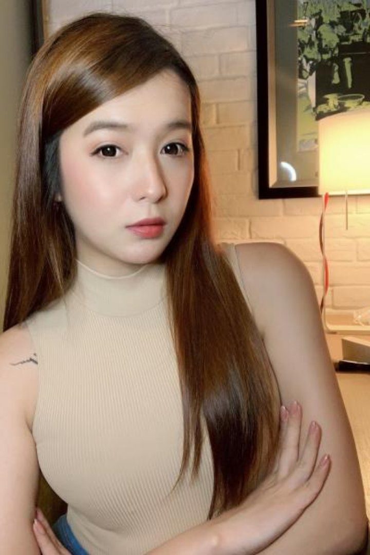 KL Escort Girl Portrait of a woman with long brown hair wearing a beige top. Malaysia Sex Service