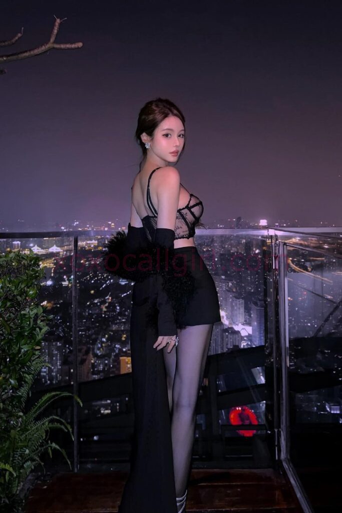 KL Escort Girl Woman in gold lingerie sits on a bed, smiling. Bedroom setting. Malaysia Sex Service